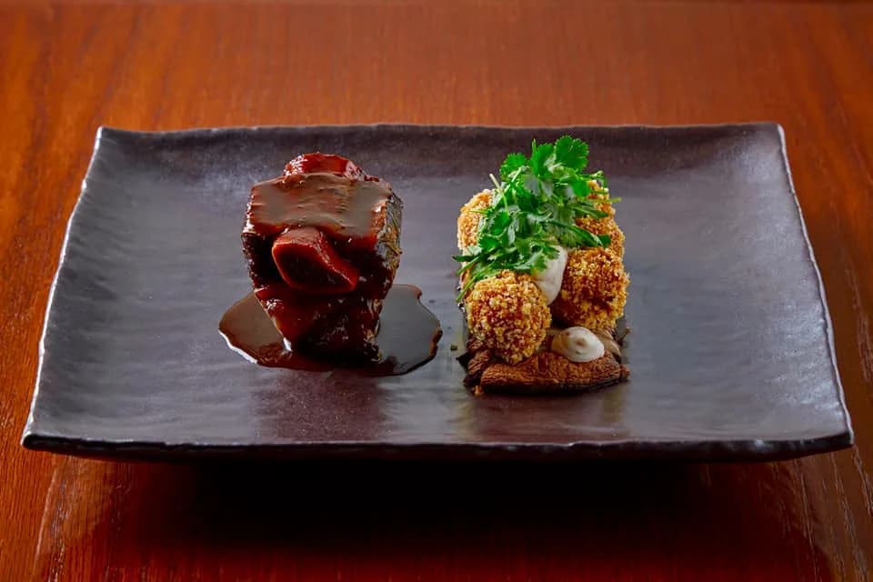 Hovězí líčka v demi-glace s krokety a petrželkou na obdélníkovém černém talíři